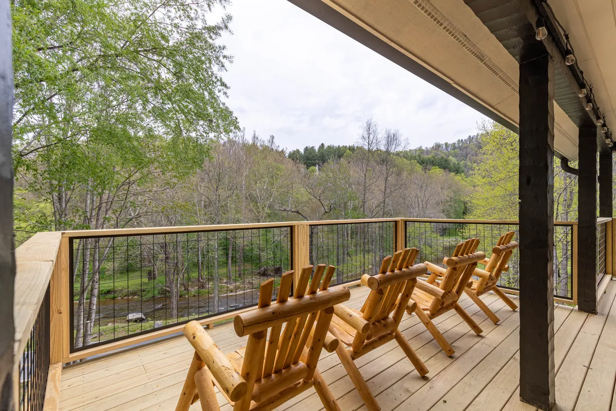 The image features wooden chairs placed on a scenic deck, overlooking lush greenery and offering a tranquil spot to relax or watch wildlife. The inviting outdoor seating highlights the idea of spending time together with your pet in a peaceful environment.
