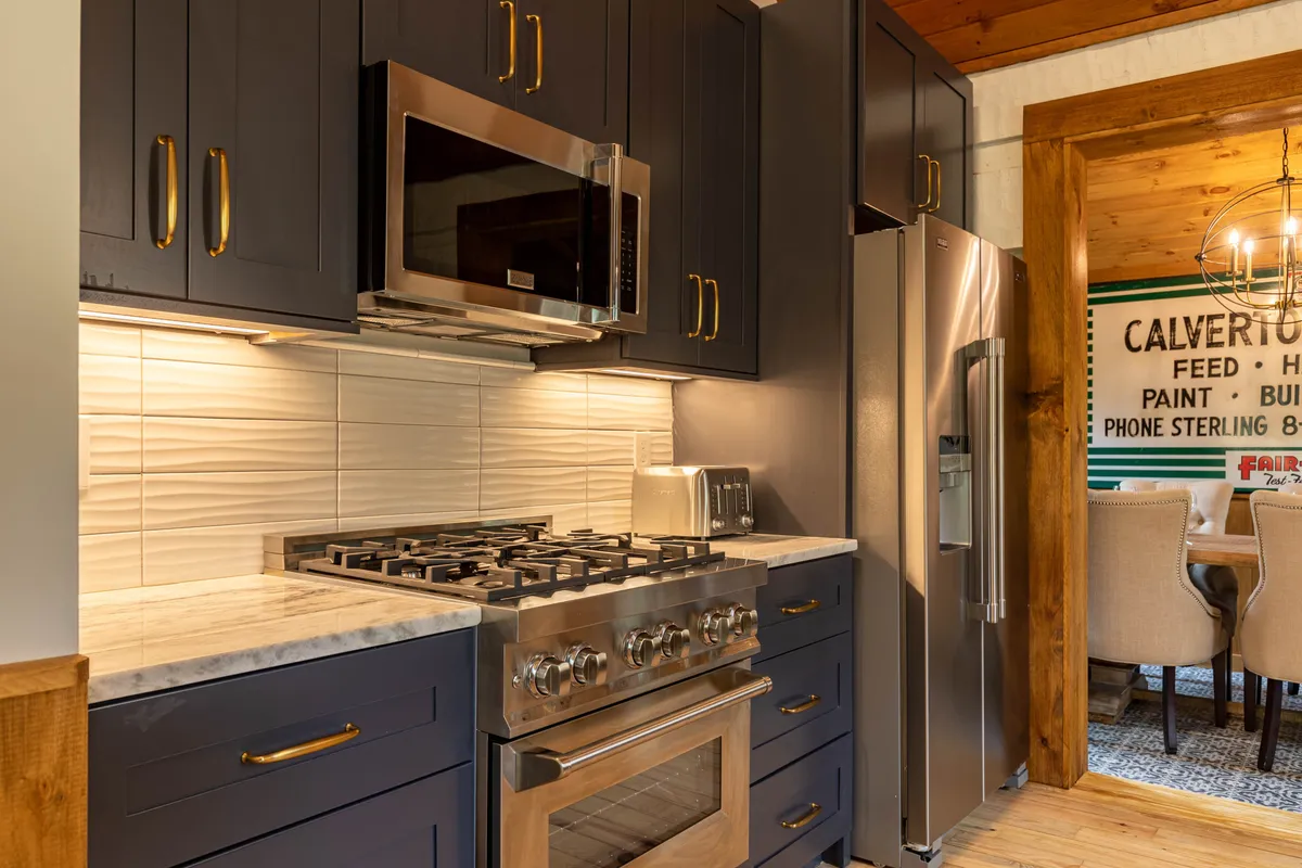 A modern kitchen with blue cabinetry, marble countertops, and stainless steel appliances. The space is bright, functional, and well-equipped, signaling an area ready for family meals and culinary adventures.