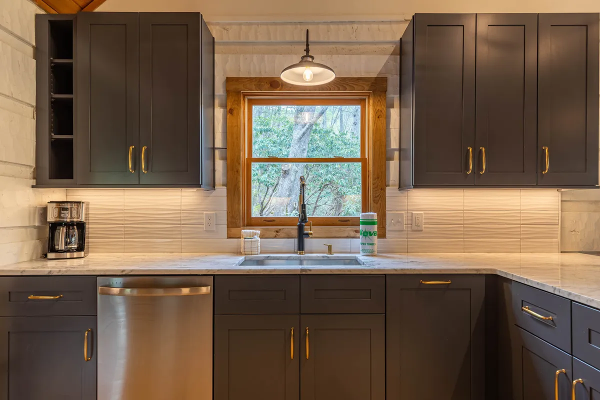A cozy kitchen nook with a farmhouse sink, window views, countertops, and warm cabinetry. The scene suggests casual dining, baking, or sharing coffee in a comfortable, welcoming setting.