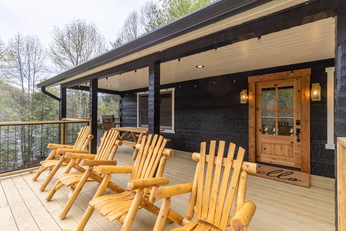 The cabin’s welcoming deck features wooden chairs facing outward, offering a perfect spot to relax and take in the natural surroundings after a day of adventure. The vantage point hints at sunrise views, stargazing nights, and a strong connection to the outdoors.